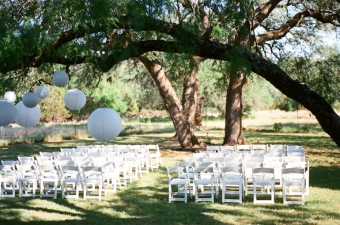 White chairs and white japanese lanterns for a wedding ceremony.
